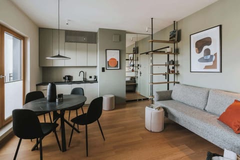 View of the living and dining area, showing seating and shelving. Contemporary design with neutral tones is evident.