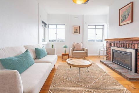 Unwind in the light-filled living area, where soft seating and a brick-surround gas fireplace bring warmth and calm in every season.