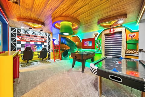 Step into a vibrant game room filled with excitement, featuring a colorful slide and bold decor that sparks joy. The glossy finish of the air hockey table and racing-inspired details create a playful atmosphere for all ages.
