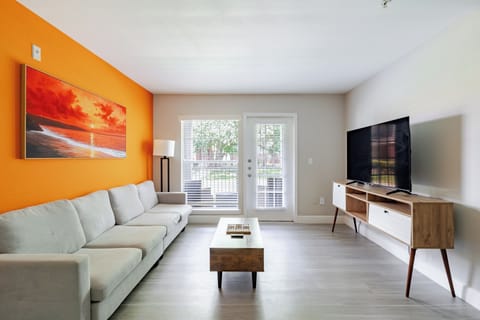 Bright modern living room with bold accent wall, big TV, and natural light