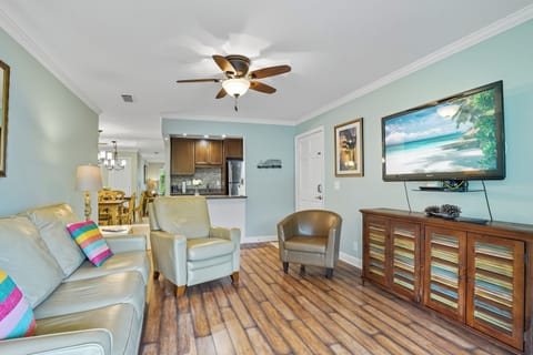 Ocean Walk J-10 Living Room and Kitchen - Open seating, wood floors, flat-screen TV, and easy flow to dining for a St. Simons condo stay near Pier Village.