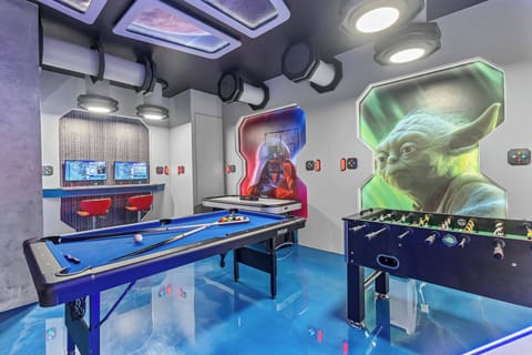 Step into a vibrant game room bursting with energy and unique decor. Enjoy the striking blue floor and colorful murals of iconic characters, then unwind on sleek bar stools after a fun game of pool or foosball.