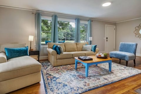 Bright and welcoming living room with comfortable seating, large windows, and modern recessed lighting. Relax after exploring Greenville with plenty of space to unwind, stream your favorite shows, or enjoy time together in this cozy, pet-friendly home.