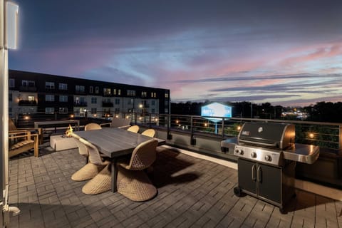 Gather around the fire pit at dusk with the city lights rising behind you, gas grill within reach and rooftop patio seating built for lingering into the night