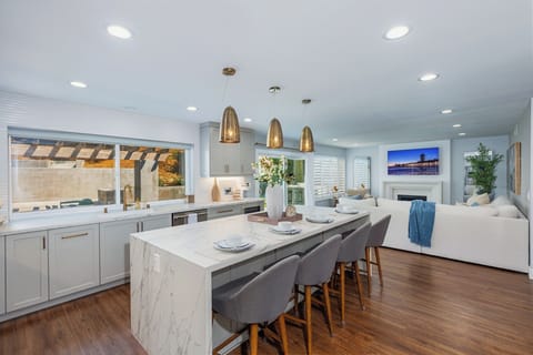 Open-concept kitchen with barstool seating, waterfall counter island, and pendant lights.