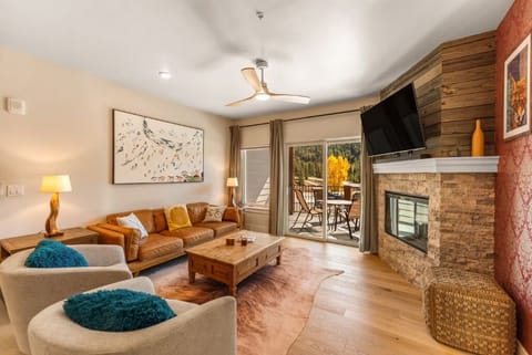 Cozy up by your stone fireplace in this warm living room, where leather seating and autumn views create the perfect mountain retreat atmosphere.