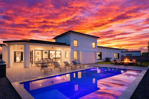 Stunning private yard with sparkling pool, sun loungers, lawn space, covered patio with lounge area, covered outdoor dining area, fire pit, and built-in BBQ grill!