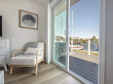 Peaceful waterfront view from a cozy sitting nook with modern décor and sliding glass doors leading to the deck. Perfect for morning coffee or evening sunsets overlooking the canal and passing boats.