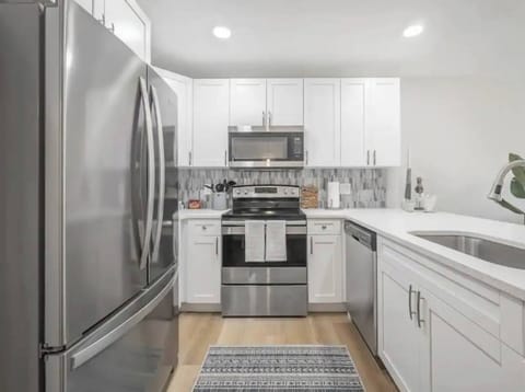 Stylish modern kitchen with stainless steel appliances, sleek white cabinetry, and elegant tile backsplash. Fully equipped for cooking and entertaining, this bright space blends function and design for a seamless culinary experience.