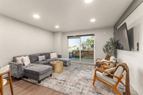 - Cozy living room with large sectional sofa perfect for movie nights and relaxing   - Natural light pours in through sliding doors leading to a private patio space   - Neutral tones and modern decor create an inviting atmosphere for every guest