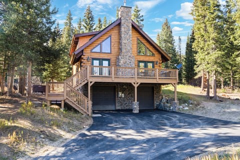 The front exterior of the cabin features a spacious driveway and tall pine trees.