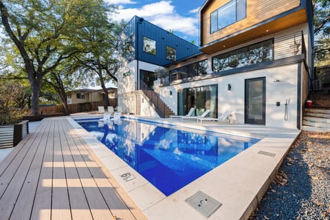 Modern home with Resort-style pool and expansive wood deck blending contemporary design with a natural, treed setting.