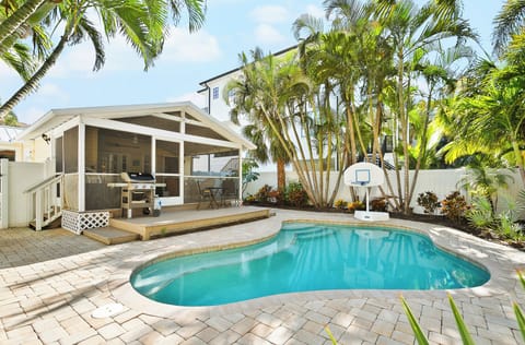 vacation rental with private pool and BBQ near the beach. - This tropical backyard features a private swimming pool, a built-in grill, and lush palm landscaping—perfect for relaxing outdoor meals after a beach day.