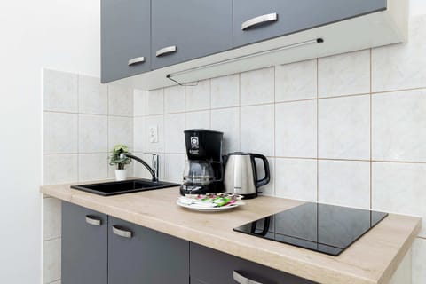 Compact yet functional kitchen equipped with essential appliances, including a coffee maker and electric kettle, complemented by a tiled backsplash.