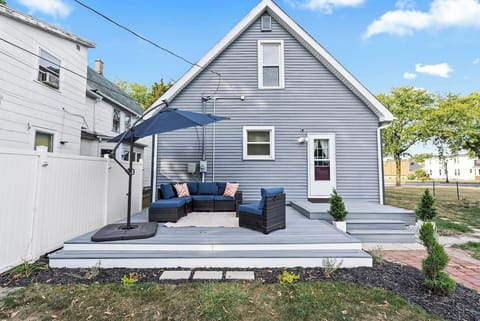 Charming backyard deck with cozy sectional seating and a large umbrella, perfect for morning coffee, evening chats, or relaxing outdoors during your stay.