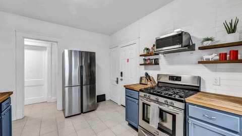 Cook, connect, and create memories in this bright and stylish kitchen featuring stainless-steel appliances, open shelving, and beautiful butcher-block counters.