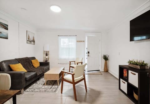 Bright living room w/ sofa seating, TV & large windows bringing in natural light