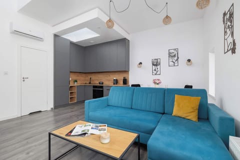 A welcoming living area featuring a blue sofa complemented by a yellow accent pillow, bathed in natural light and decorated in a contemporary style.