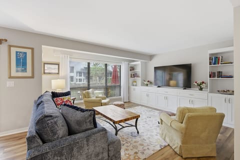 Bright living room with large windows, built-in shelving, and comfortable seating for relaxing.