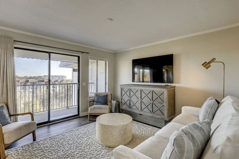 Relax in the modern living room with a large flat-screen tv and balcony access.