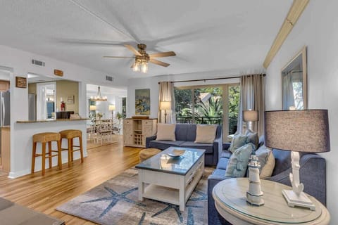 Relax in your spacious living area with soaring ceilings, warm wood floors, and a cozy ceiling fan creating the perfect atmosphere.