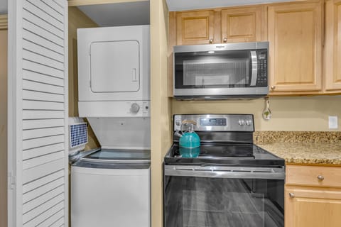 Your fully equipped kitchen features everything you need, including convenient in-unit laundry facilities tucked neatly behind louvered doors for a seamless cooking experience.