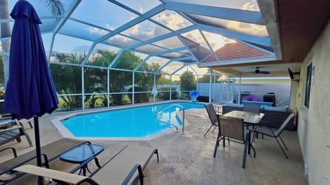 Screened pool enclosure with pool, outdoor dining table, and lounge chairs on the patio