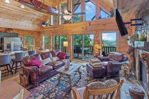 Escape to this stunning mountain retreat featuring cozy leather seating, a stone fireplace, panoramic views, and a spacious deck perfect for relaxing or dining outdoors. The perfect blend of rustic charm and modern comfort awaits!