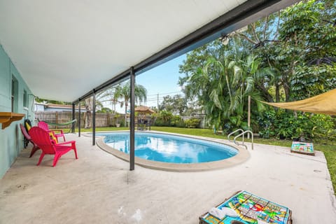 Covered patio area overlooking a private pool surrounded by lush greenery.