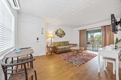 Relax in this bright living room with a balcony view of palm trees.