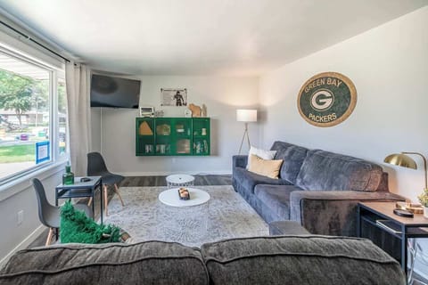 Relax in the spacious living room featuring a plush sectional, smart TV, and stylish décor—perfect for game day lounging or movie nights after exploring Green Bay.