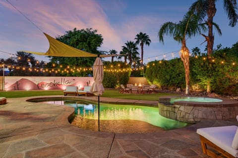 Resort-style backyard at dusk w/ glowing pool, palms & lounge areas made for unforgettable desert nights.