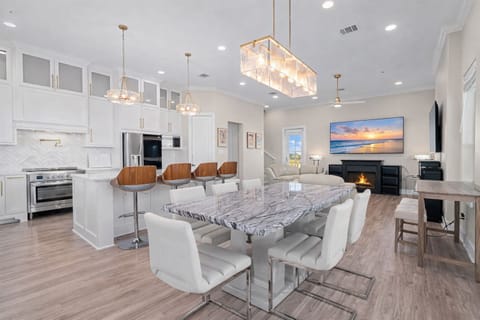 Spacious modern kitchen and dining area with large island, bar seating, and designer lighting, ideal for family gatherings in this luxury Galveston beach house.