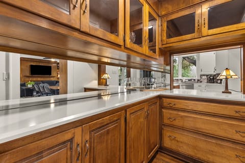 Sip and socialize in this charming bar nook with warm wood cabinetry and vintage glass accents.