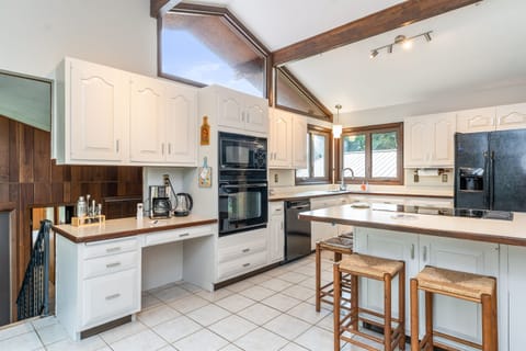 Bright and spacious kitchen featuring vaulted ceilings, modern appliances, and a cozy coffee station—perfect for cooking and gathering.