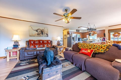 Living Room | Features leather seating, rustic armchair, stone fireplace with TV, and deck access.