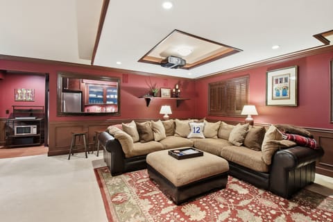 Theater room/living room area with view of kitchen area in back and bar seating.