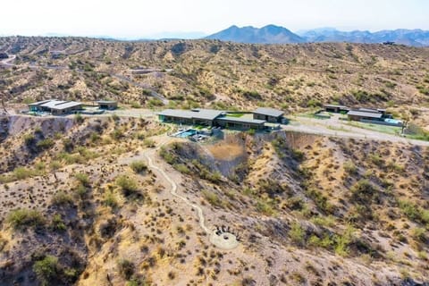 Estate 3: Stunning private oasis featuring a sparkling heated infinity pool and spa with sun loungers, a patio with a BBQ grill, multiple lounge areas, and fire pits surrounded by unparalleled desert views.