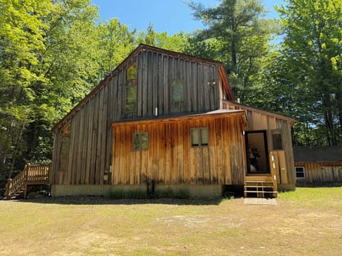 A rustic two-story cabin nestled in a forested area in Sanbornton, NH.