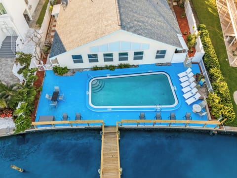 Top-down view of pool, dock, and loungers by the bay.