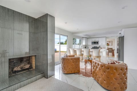Stylish lounge area with chic leather seating and a modern fireplace, seamlessly connected to the kitchen and dining space.
