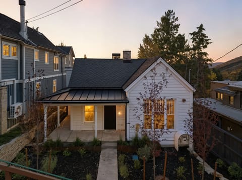 Charming white vacation home at sunset with modern architectural design and mountain backdrop.