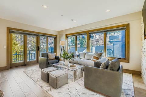 Unwind in our chic open-concept living area, featuring a comfortable sectional, additional seating, and a glass coffee table. This bright, relaxing space is perfect for enjoying the views.