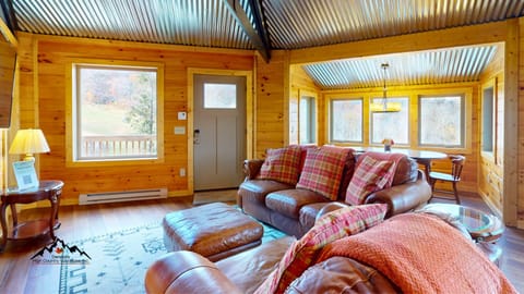 Cozy mountain living room with comfortable seating, warm rustic-modern charm, and easy access to the deck overlooking Sugar Mountain slopes and year-round mountain scenery.