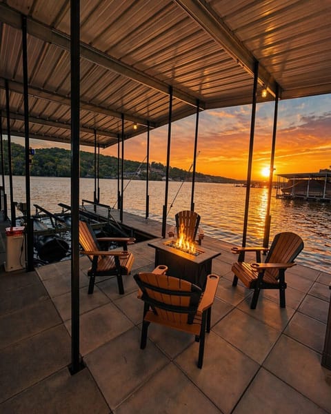 Waterfront dock retreat with covered lounge, fire pit seating, and breathtaking sunset lake views—perfect for relaxing evenings, boating, and luxury lakefront getaways.