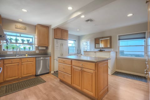Sunny kitchen with island and stainless dishwasher.
