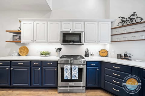 Gourmet chef's kitchen featuring dark navy custom cabinetry, quartz countertops, stainless steel appliances, and a spacious island. Modern design with all amenities for preparing memorable meals