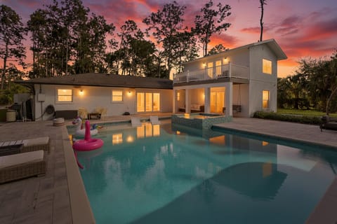 Saltwater pool & spa with cabana, loungers and tropical landscaping at sunset.