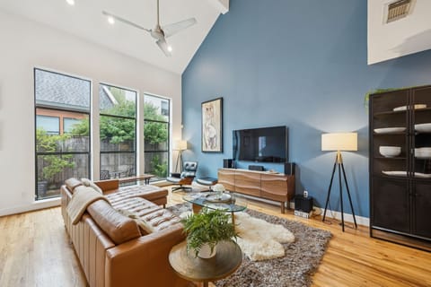 Sun drenched living room featuring smart TV, leather couch & luxury touches