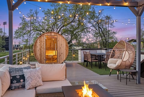Rooftop oasis with sauna, fire pit, egg chair & dining under lights